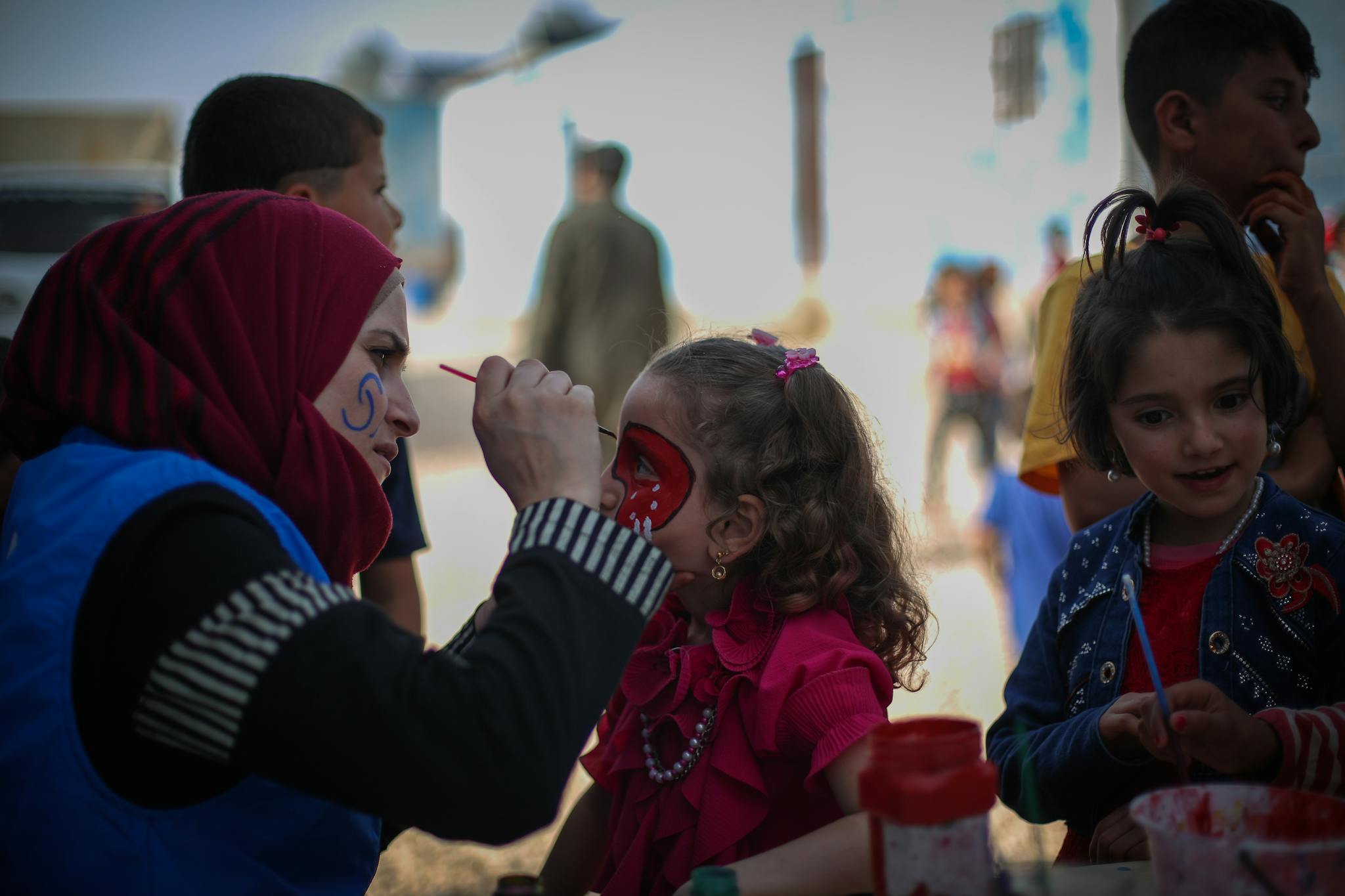A lively face painting session with children in outdoors setting, Idlib, Syria.